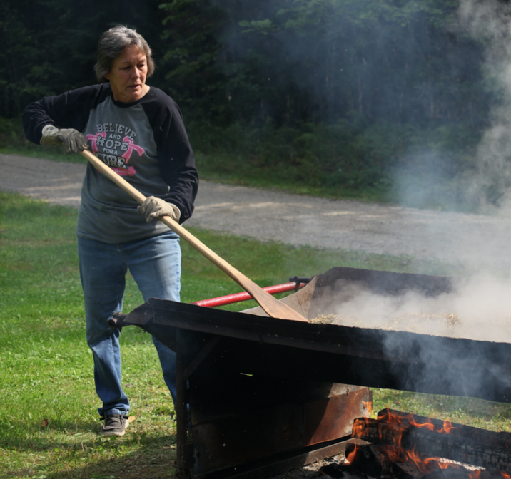 Woman roasting wild rice over a fire.