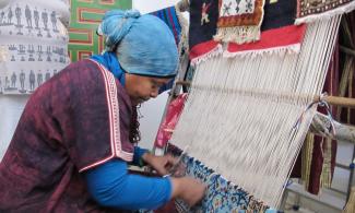 Woman making a carpet on a hand loom.