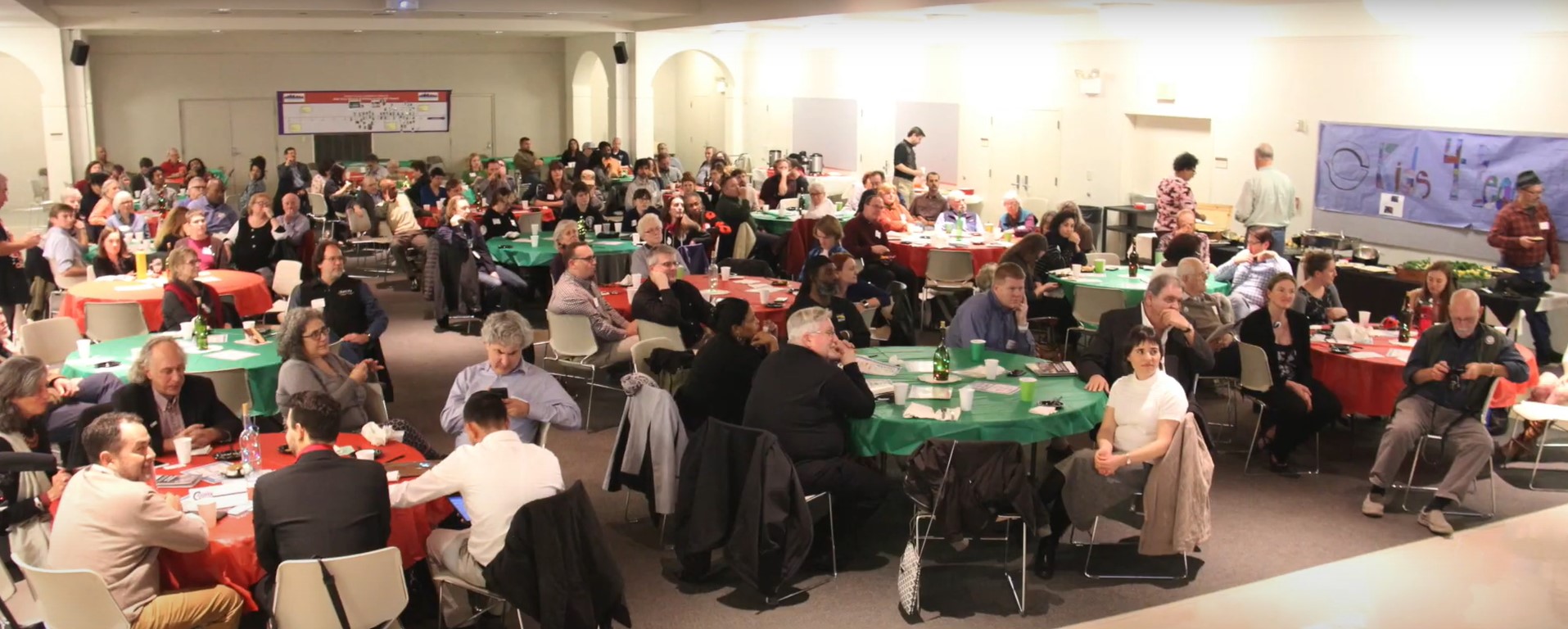 A large room full of people sitting at tables for the UCC 10th Anniversary gathering.
