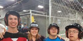 Developmental Services Worker Co-operative member with three clients at a batting cage.