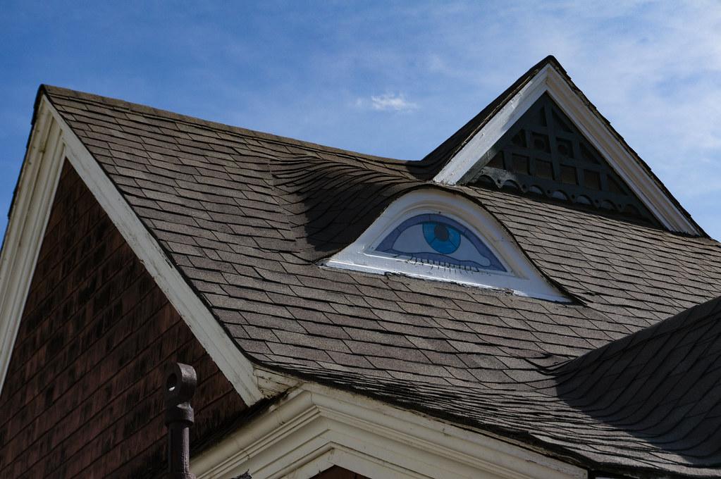 Gable on the roof of a house painted to look like an eye.